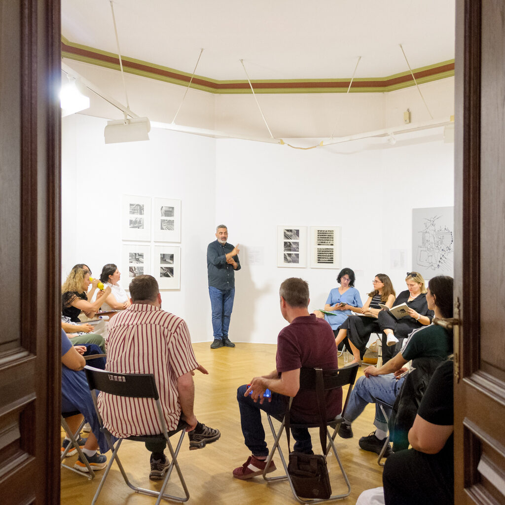 Group in museum space around the artwork and the sign language interpreter standing next to it