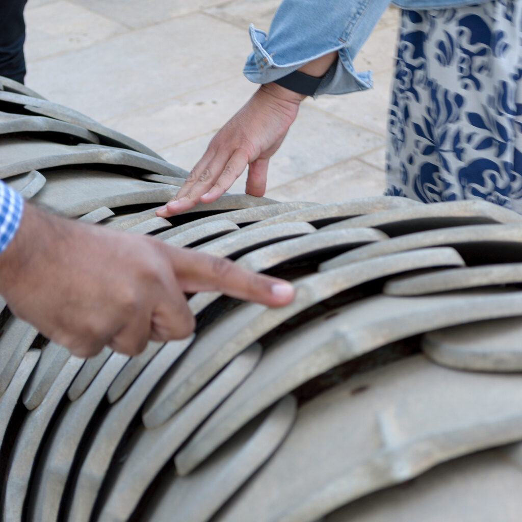 Fingers touching the aluminum scales of the snake's tail