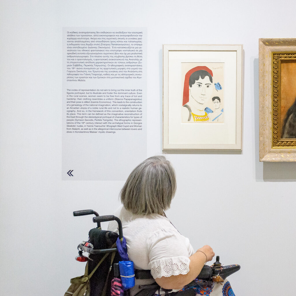 Woman in a wheelchair viewing the artwork on the wall.
