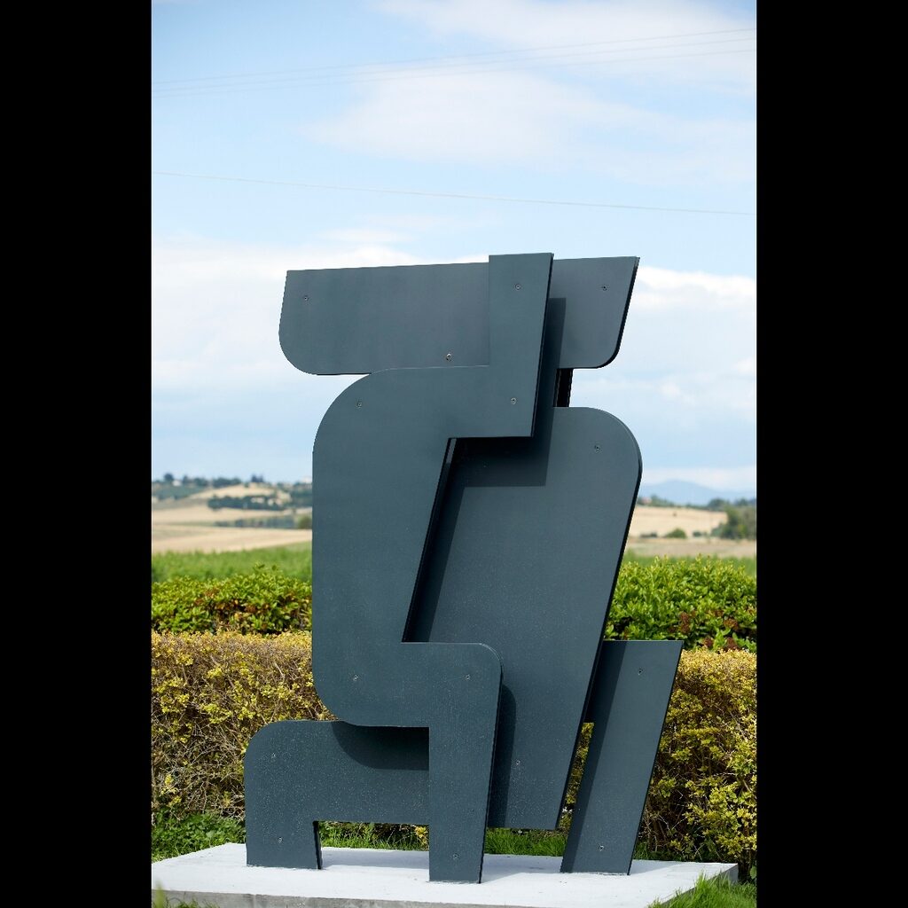 Abstract metal sculpture outdoors with green landscape in the background