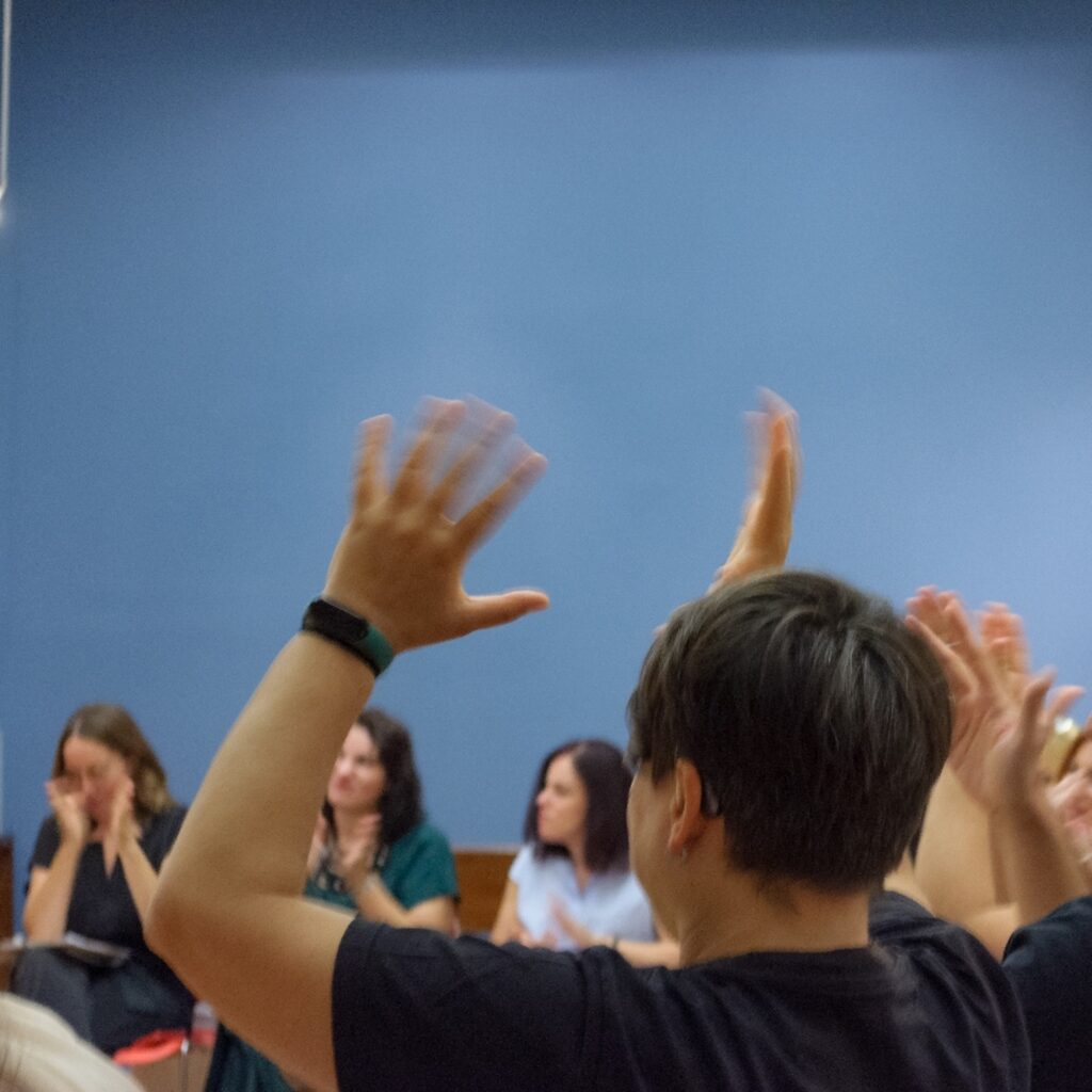Participants raising hands clapping in. sign language at the end of the meeting point.