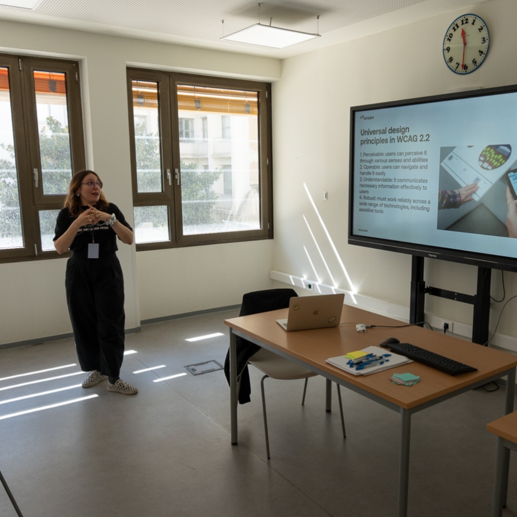 Christina Vlachou, the moderator of the workshop talking in front of the presentation slide on universal design in digital space.