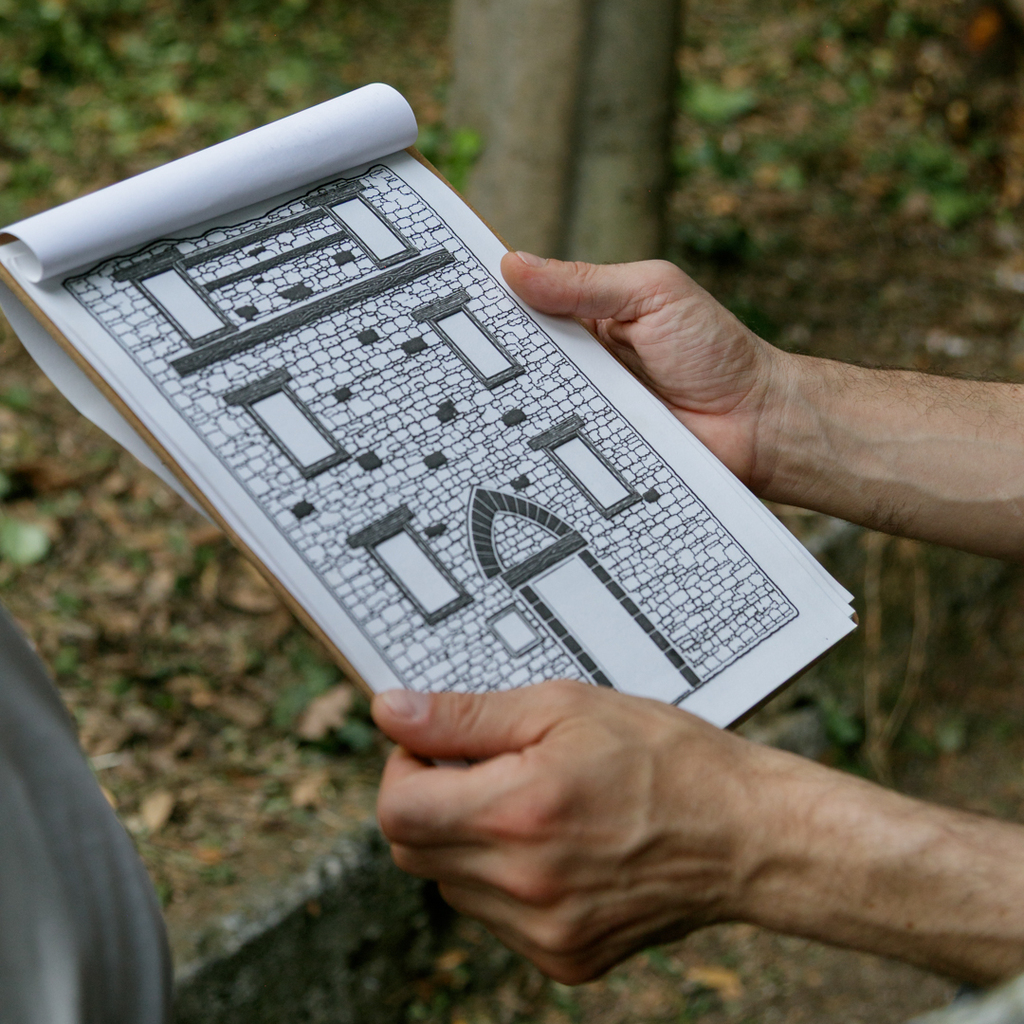 Hands holding a tactile image of a historic building's facade.