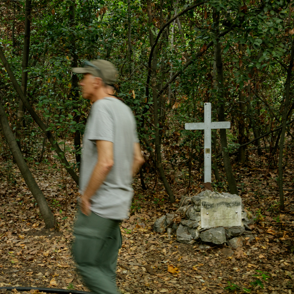 Participant walking past an iron cross in the garden.